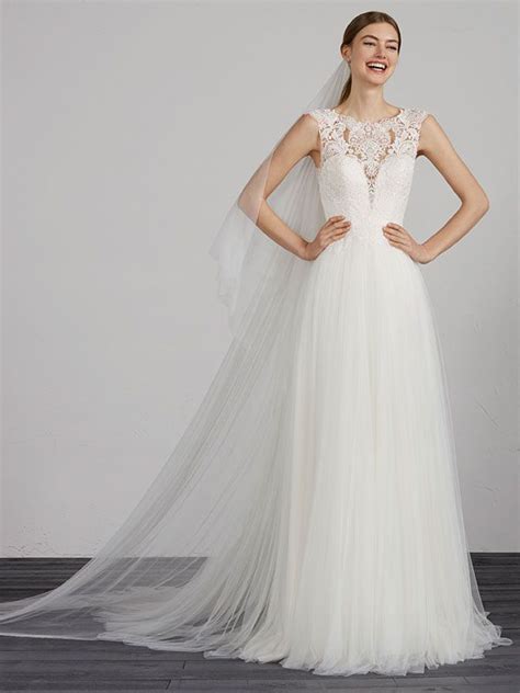Foto über rüschen eines hochzeitskleides im sand. Brautkleid mit Spitzenapplikationen auf dem Oberteil und ...