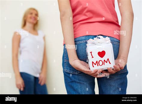 Close Up Of Teenage Girl In Jeans Holding Tbox For Mom Behind Her