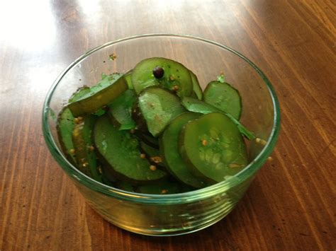 A Glass Bowl Filled With Sliced Cucumbers On Top Of A Wooden Table
