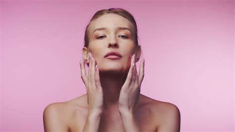 Model Rubbing Face Cream Into Her Face While Smiling At The Camera