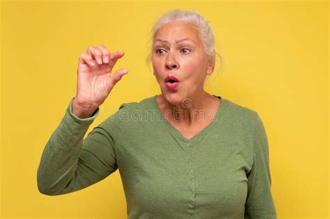 Surprised Senior Woman Shows Something Small With Hands Stock Photo