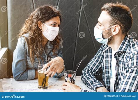 Engaged Couple Sitting In A Cafe Wearing Surgical Masks During
