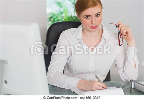Stern Businesswoman Working At Her Desk Looking At Camera In Her Office