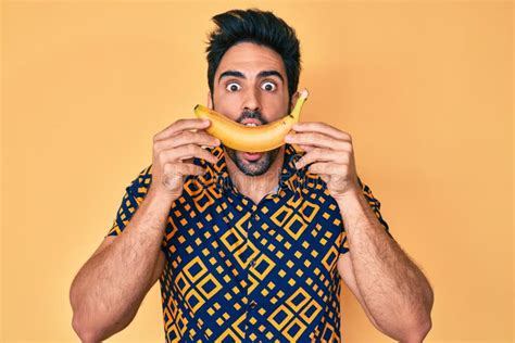 Handsome Hispanic Man With Beard Holding Banana Like Funny Smile Celebrating Crazy And Amazed