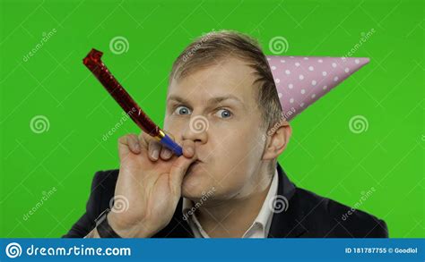 Drunk Disheveled Young Businessman In Festive Cap Celebrates Blowing A Whistle Stock Image