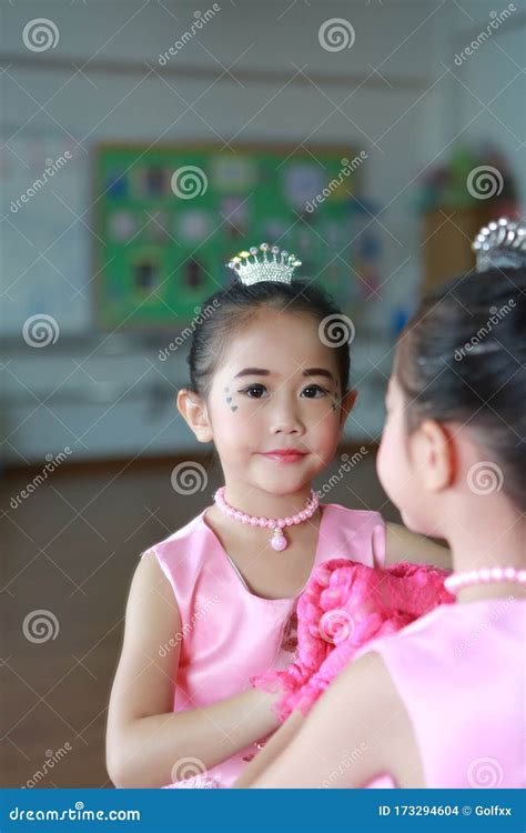 Adorable Little Asian Ballerina Girl In A Pink Tutu Posing With Mirror Reflection And Looking At