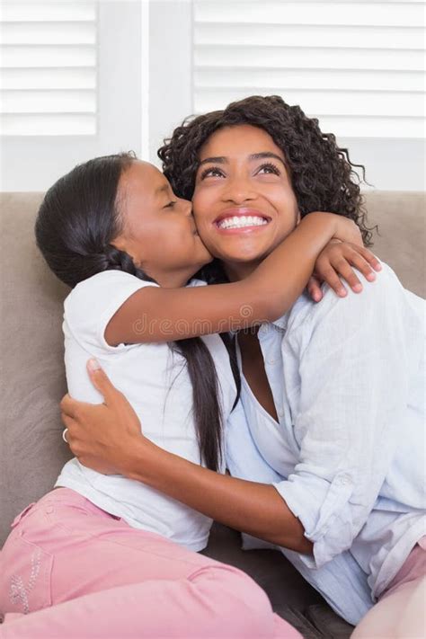 Pretty Mother Sitting On The Couch With Her Daughter Kissing Her Cheek Stock Image Image Of