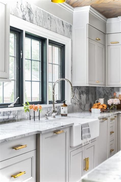 Combine style and function with a new kitchen sink. Elegant light gray and gold kitchen is fitted with a ...