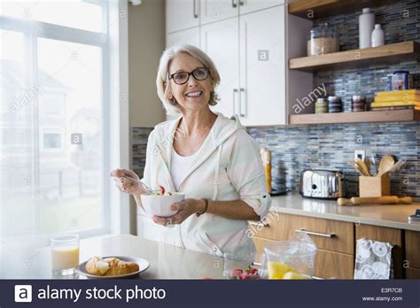 Smiling Woman Eating Fruit Salad In Kitchen Stock Photo Alamy