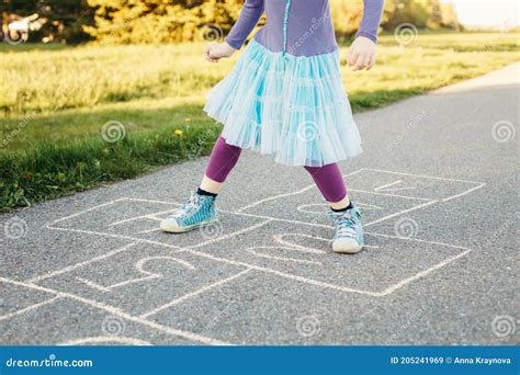 Closeup Of Child Girl Playing Jumping Hopscotch Outdoors Funny