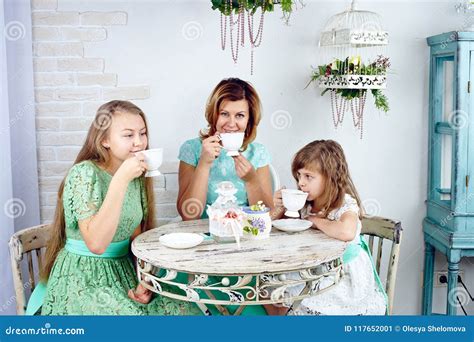 Portrait Of Happy Mother Drinking Tea With Her Two Daughters Stock