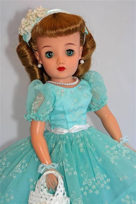 A Doll Is Wearing A Blue Dress And Holding A White Purse