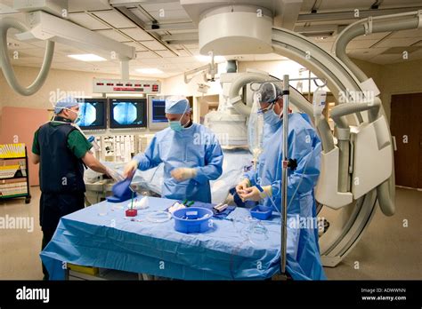 Doctors Performing Angiogram Procedure In Cardiac Cath Lab Stock Photo