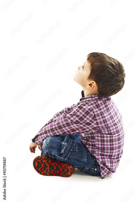 Portrait Of A Cute Little Boy Sitting On The Floor Looking Up