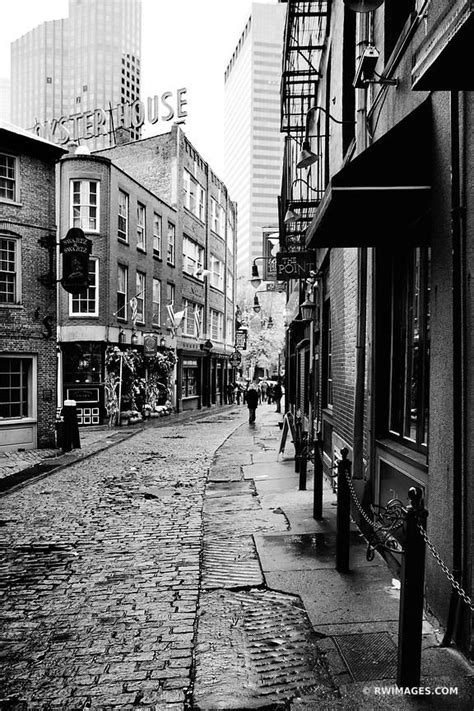 Black And White Photograph Of People Walking Down An Alleyway In A City