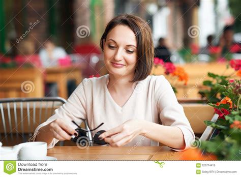 Young Woman Drinks Coffee In Cafeteria And Posing With Sunglasses Stock