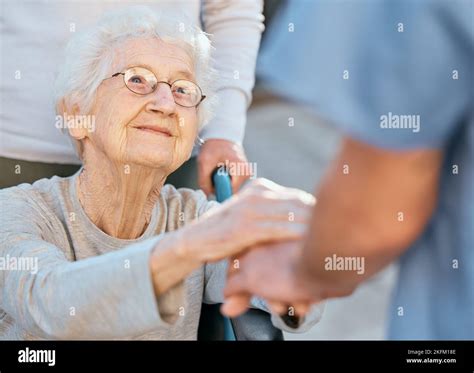Holding Hands Caregiver And Senior Woman In Wheelchair For Support