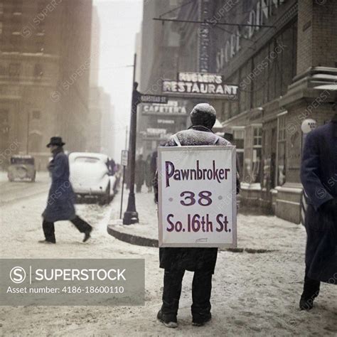 1930s winter street scene of man wearing pawnbroker sandwich board superstock
