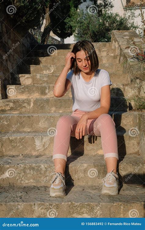 Portrait Of Young Pretty Girl Sitting On Stairs Touching Her Short Hair
