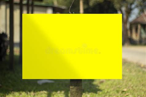 A Large Yellow Sign Board Hanging With A Pole And The Background Blur