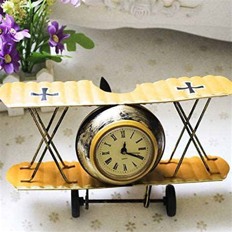A Small Airplane Clock Sitting On Top Of A Table Next To A Vase With