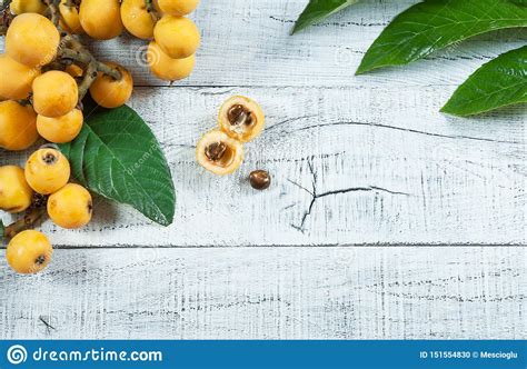 Fresh Ripe Loquat Japanese Medlar Fruit With Branch And Leaf On Wooden