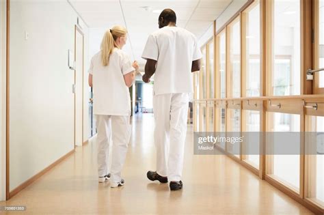 Full Length Rear View Of Male And Female Nurse Walking In Hospital