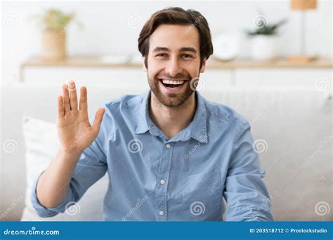 Happy Man Waving Hand To Camera Sitting At Home Stock Photo Image Of