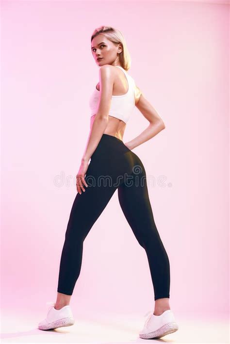 Slim Woman In Sportswear With Hands On Weist Stands On Embankment Stock