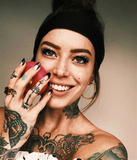 a woman with tattoos on her arm holding a cell phone