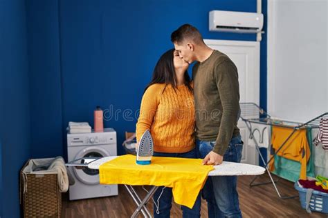 Man And Woman Couple Kissing And Hugging Each Other Ironing Clothes At Laundry Room Stock Image