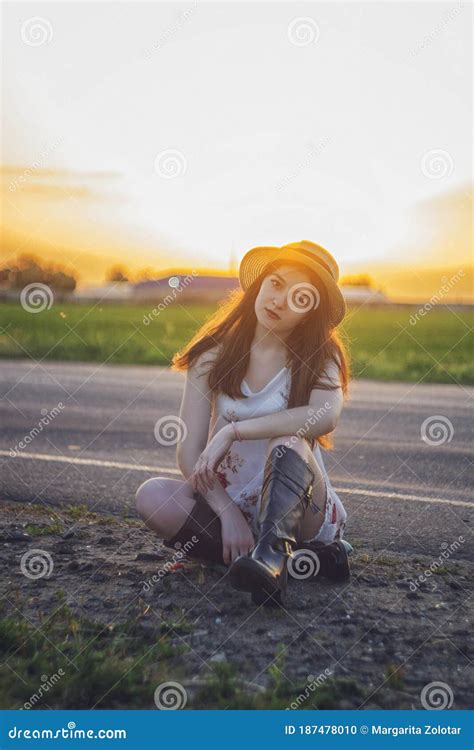 Beautiful Brunette Girl Sitting In The Middle Of An Empty Road Stock