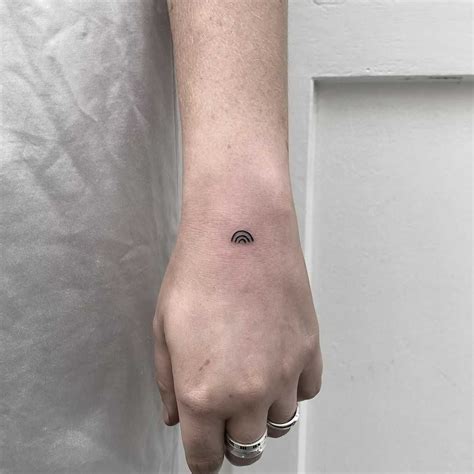 A Minimalist Black Rainbow Tattooed On The Left Hand By Rich Sinner