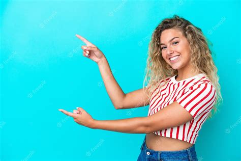 Premium Photo Girl With Curly Hair Isolated On Blue Background Pointing Finger To The Side And