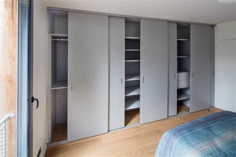 A Bedroom With White Closets And Wooden Flooring Next To A Bed In Front