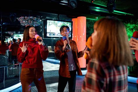 Group Of Friends Having Fun And Singing Songs At Karaoke Club Stock