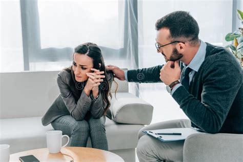 Psychologist Touching Shoulder Of Crying Patient In Doctors Stock Image