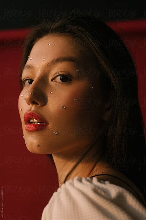 Closeup Portrait Of An Asian Girl With Red Lips And Crystals On Her Face In Warm Light By