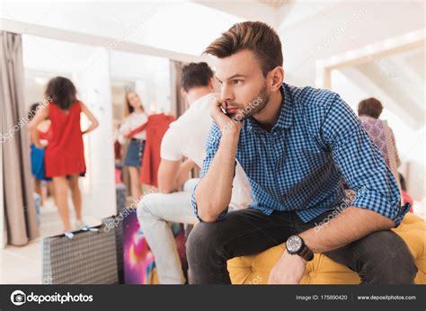 man in the dressing room is waiting for his girlfriend girl tries on things in the fitting room