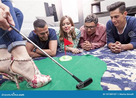 Group Of Young Adults Have Fun Playing Golf In The Living Room Stock