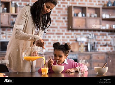 Mother Pouring Juice Into Daughter S Glass During Breakfast At Home Stock Photo Alamy
