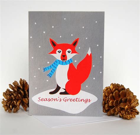 A Christmas Card With A Red Fox Holding A Blue Scarf