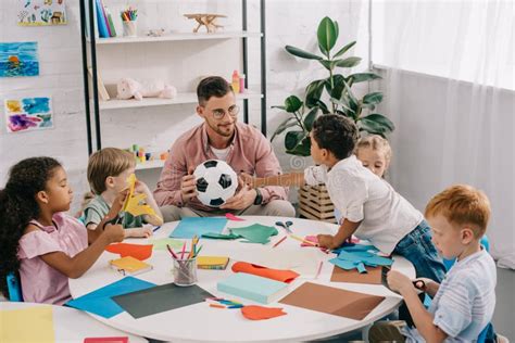 Teacher And Multiracial Preschoolers With Colorful Papers And Scissors