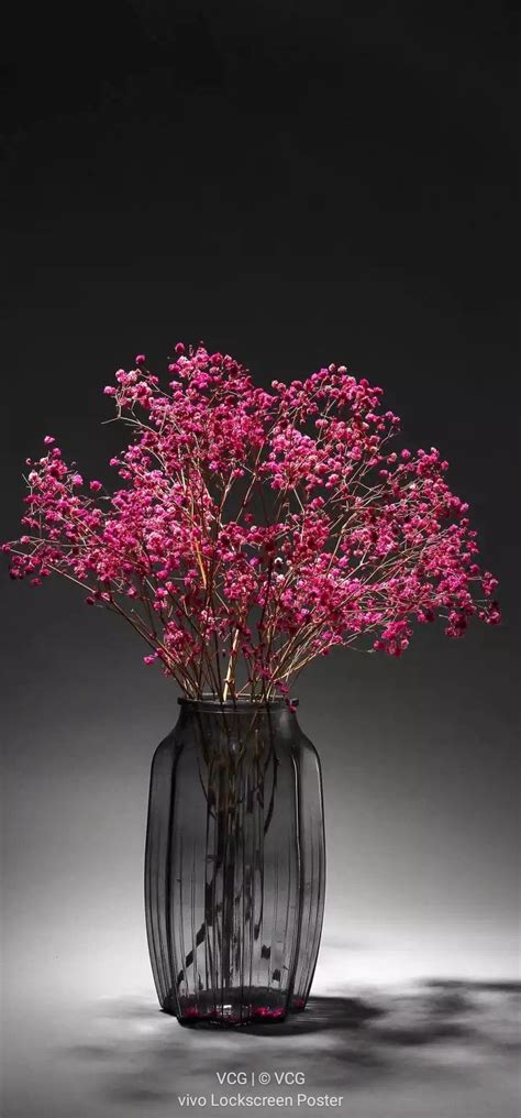 A Glass Vase Filled With Pink Flowers On Top Of A Table Next To A Black
