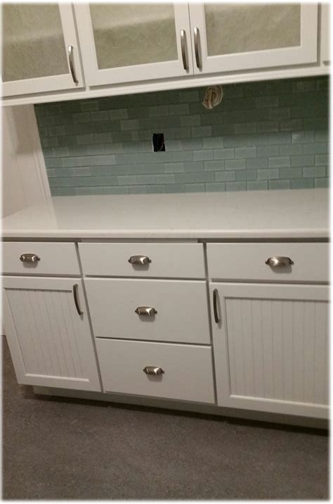 Glass subway tile backsplash, cabinets with cup pulls, upper cabinets have glass inserts ...
