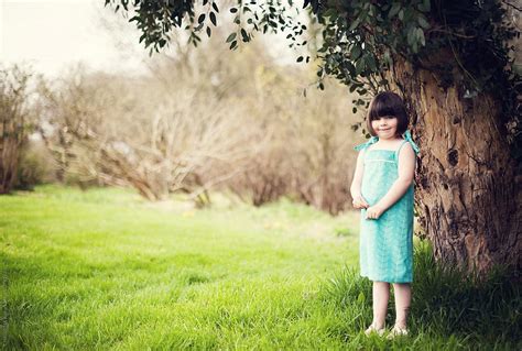Portrait Of A Little Girl Standing Under A Tree By Stocksy