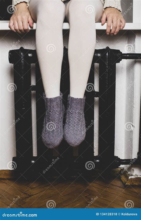 The Girl Sits On The Windowsill And Heats Her Legs In Knitted Woolen