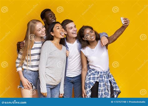 Cheerful Group Of Multiethnic Friends Taking Selfie Over Yellow