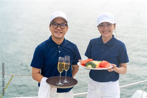 Portrait Of Waiter And Waitress Holding Fresh Fruit And Champagne For Serving To Passenger