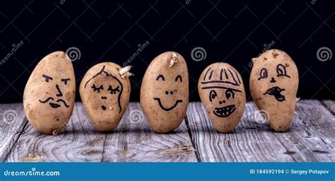 Funny Potato With A Painted Face On A Wooden Table And On A Black